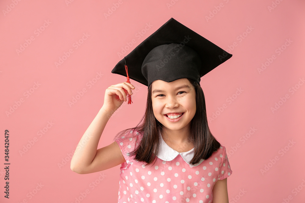 Little girl in graduation hat on color background