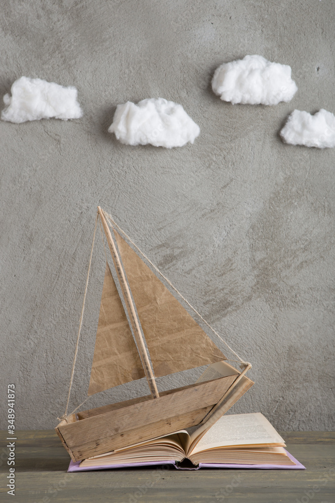 Education is a journey concept, toy boat and books like a sea waves on the wooden table, inspiration