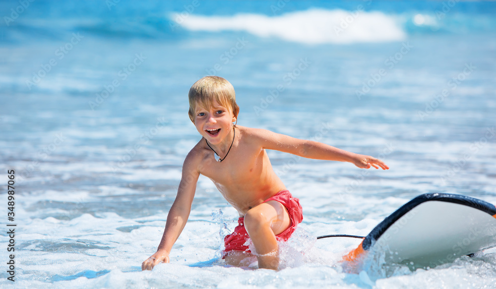 快乐男孩-年轻的冲浪者学习骑行，从冲浪板上有趣地跳下，跑向海滩。活跃的家庭li
