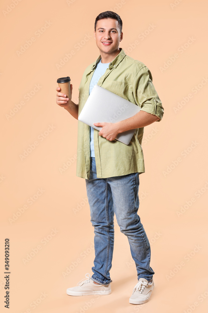彩色背景下拿着笔记本电脑和咖啡的年轻人的肖像