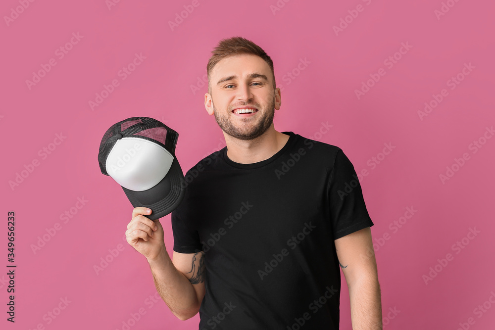 Handsome man with stylish cap on color background