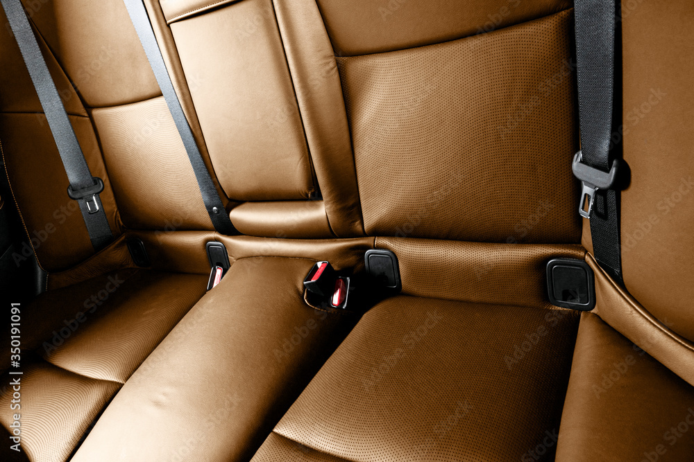 现代豪华汽车的后排乘客棕色座椅。橙色穿孔皮革，白色缝线。汽车