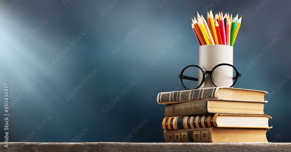 桌子上的一摞旧书和彩色铅笔
