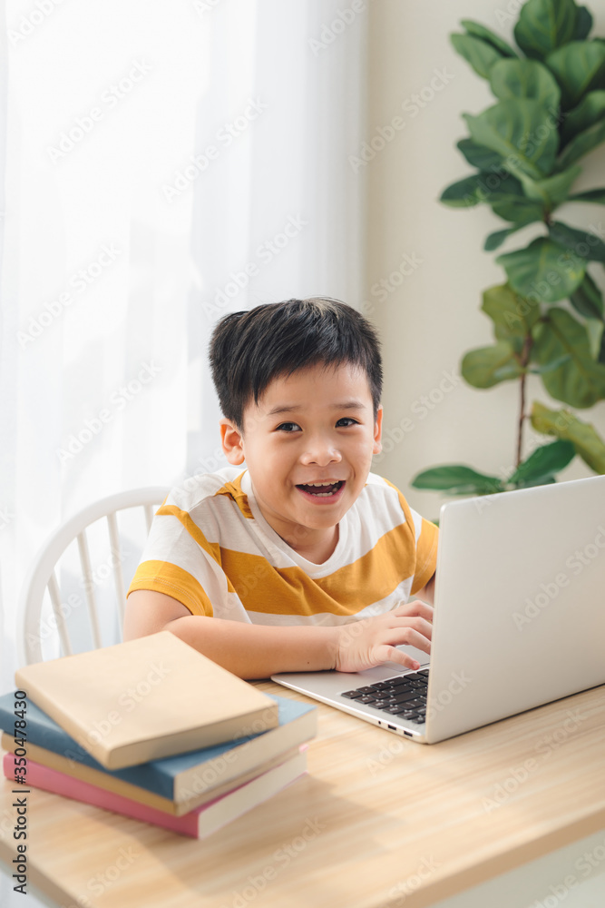 Asia preteen boy studying online on laptop with smiling and fun face at home. online education and e