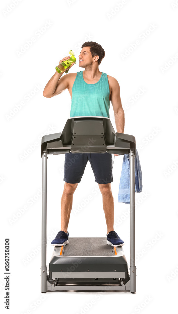 运动型年轻人在白色背景下在跑步机上训练后喝水