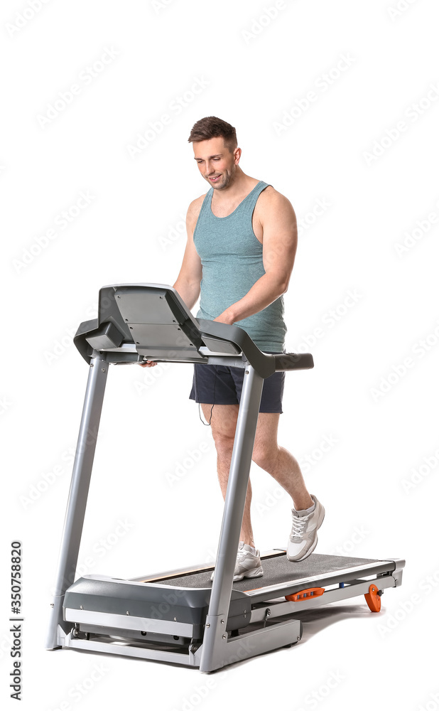 Sporty young man training on treadmill against white background