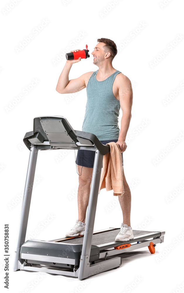 运动型年轻人在白色背景下在跑步机上训练后喝水