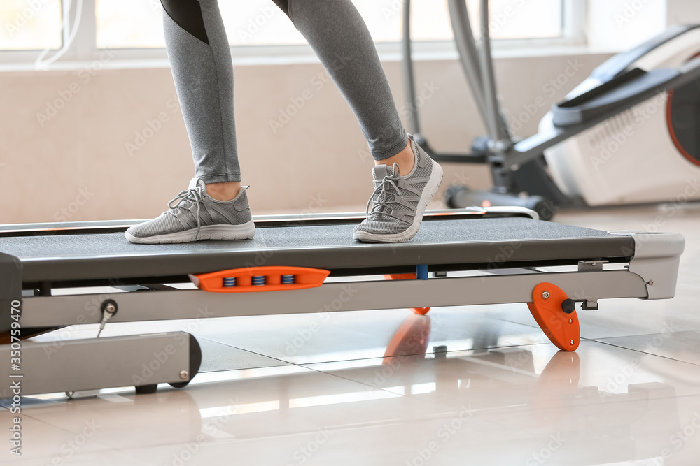 运动型年轻女子在健身房跑步机上训练