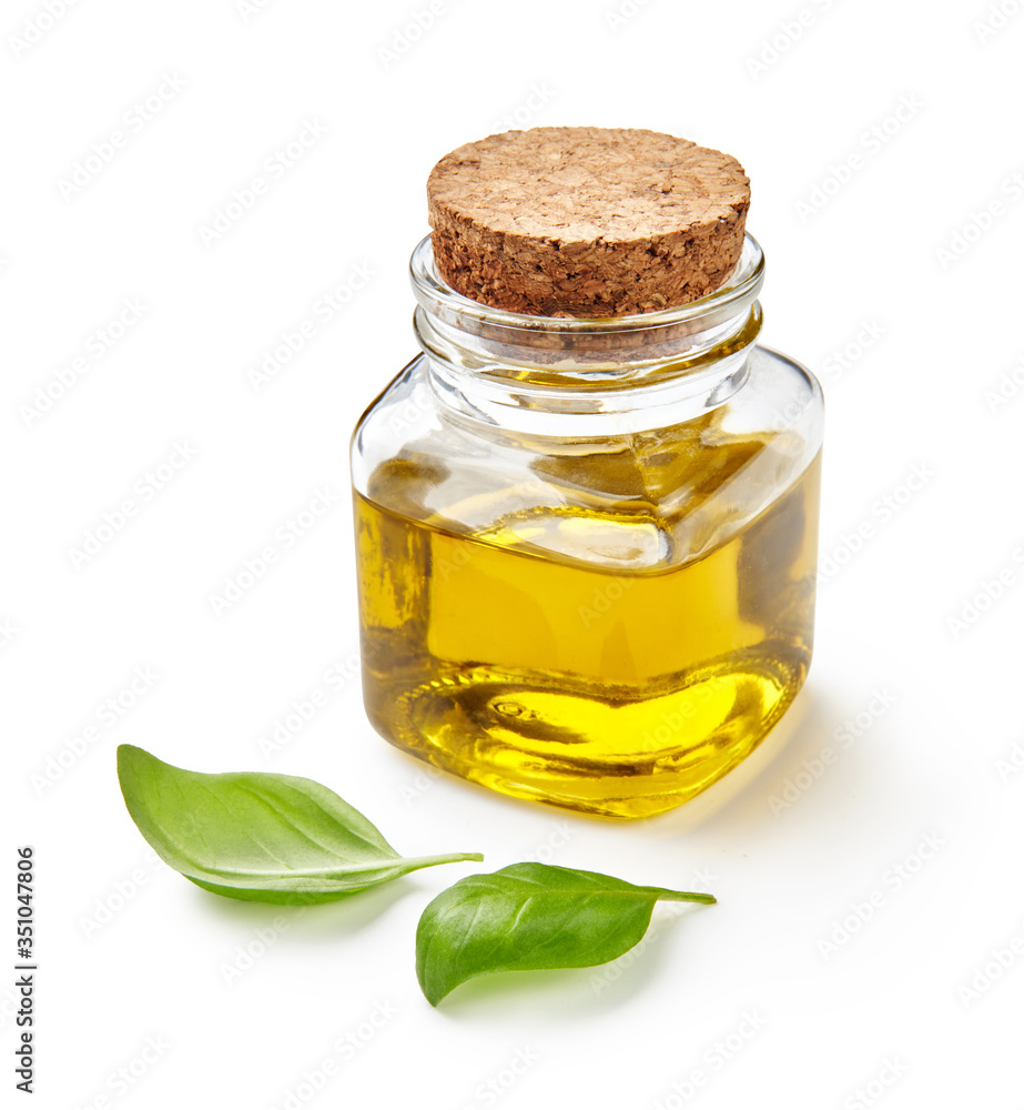 玻璃罐橄榄油或植物油，罗勒叶隔离在白色上。
