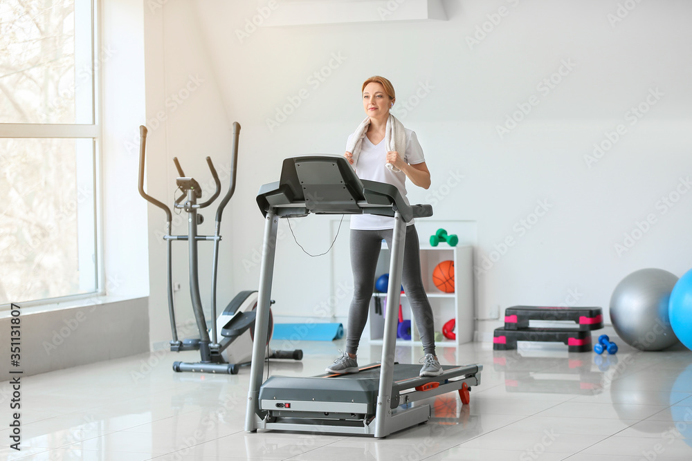 运动型女性在健身房跑步机上训练
