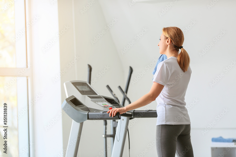 运动型女性在健身房跑步机上训练后休息