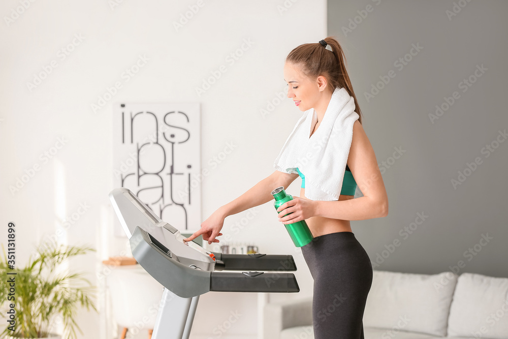 运动型年轻女性在家跑步机上训练