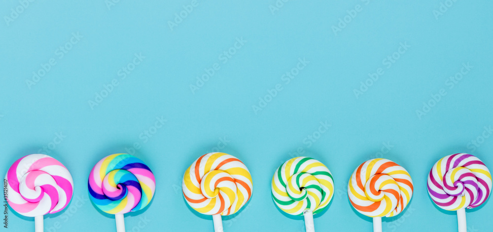 蓝色粉彩纸背景上的美味棒棒糖，一套逼真的螺旋条纹彩色棒棒糖