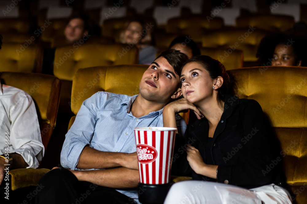 一对夫妇和一名观众在电影院看电影。团体娱乐活动和