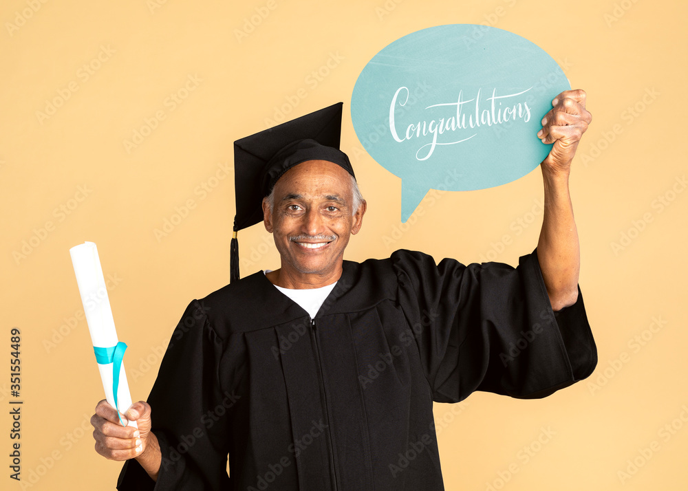 骄傲的大四学生穿着毕业礼服，手里拿着祝贺演讲的泡泡模型
