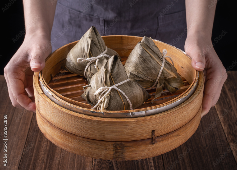 粽子，粽子——黑色背景下木桌上的一包中国传统熟食