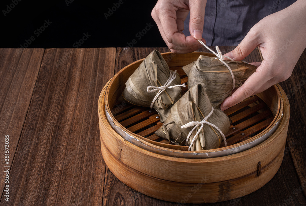 粽子，粽子——黑色背景下木桌上的一包中国传统熟食
