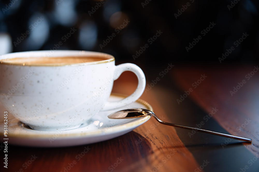 带泡沫的咖啡，一个白色质地的马克杯和一个金属勺子放在一根棍子上，特写，一米内的卡布奇诺