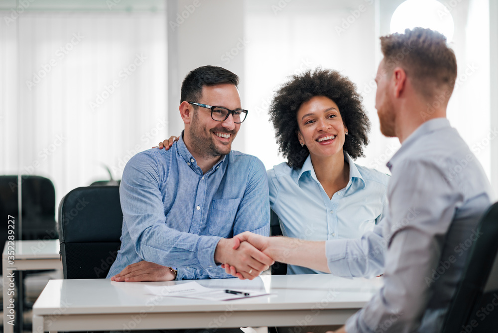 Good deal concept. Smiling man shaking hands with businessman while having support from his wife.