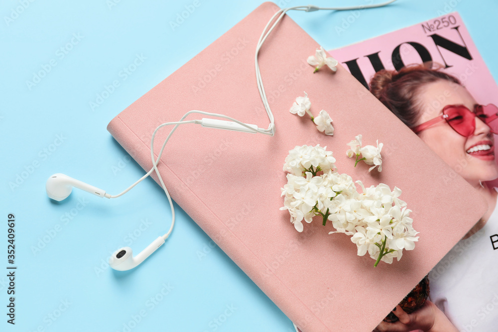 以美丽的淡紫色花朵、耳机、笔记本和时尚杂志为背景的构图