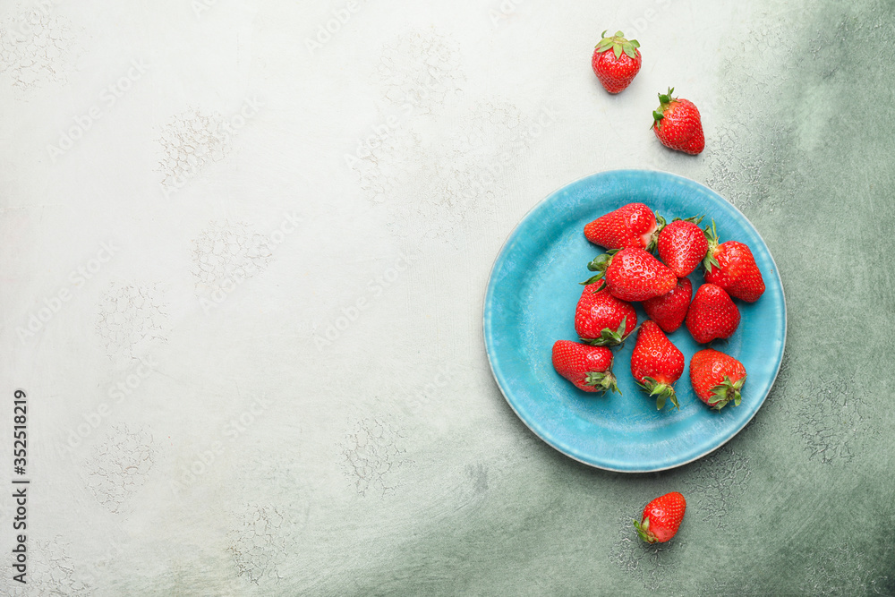 Plate with ripe strawberry on color background
