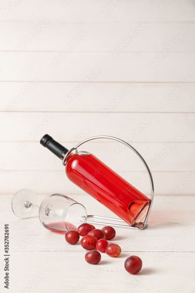 白色木质背景上装有葡萄酒和玻璃杯的支架