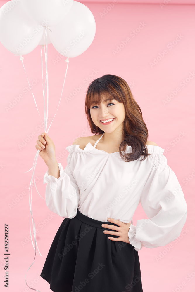 美丽的女孩带着白色的气球大笑，被隔离在粉红色的背景上