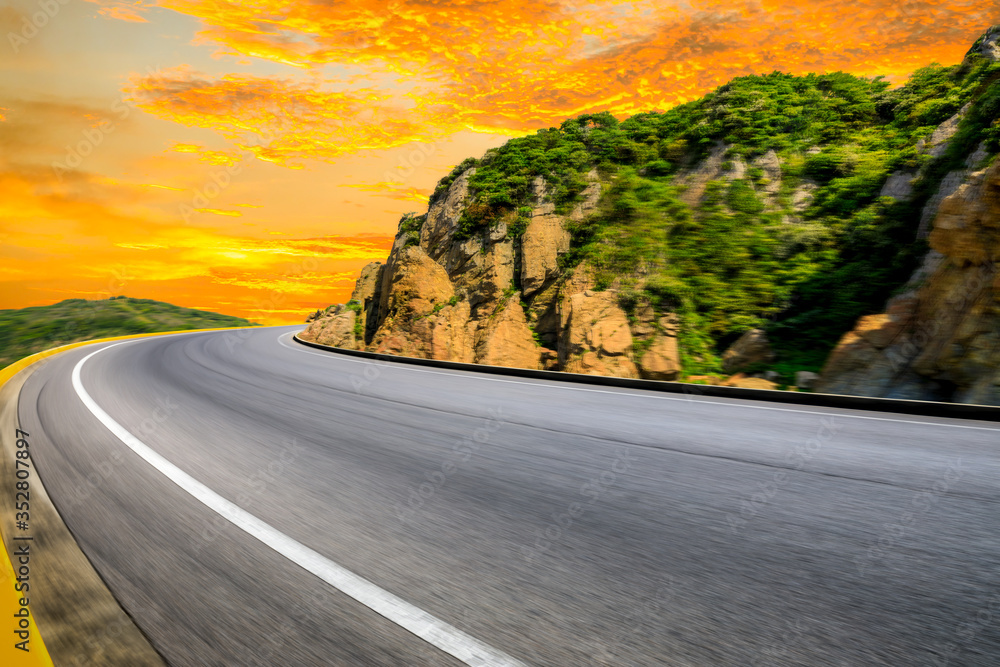 Motion blurred mountain road,asphalt roads and mountains with sky clouds at sunset.