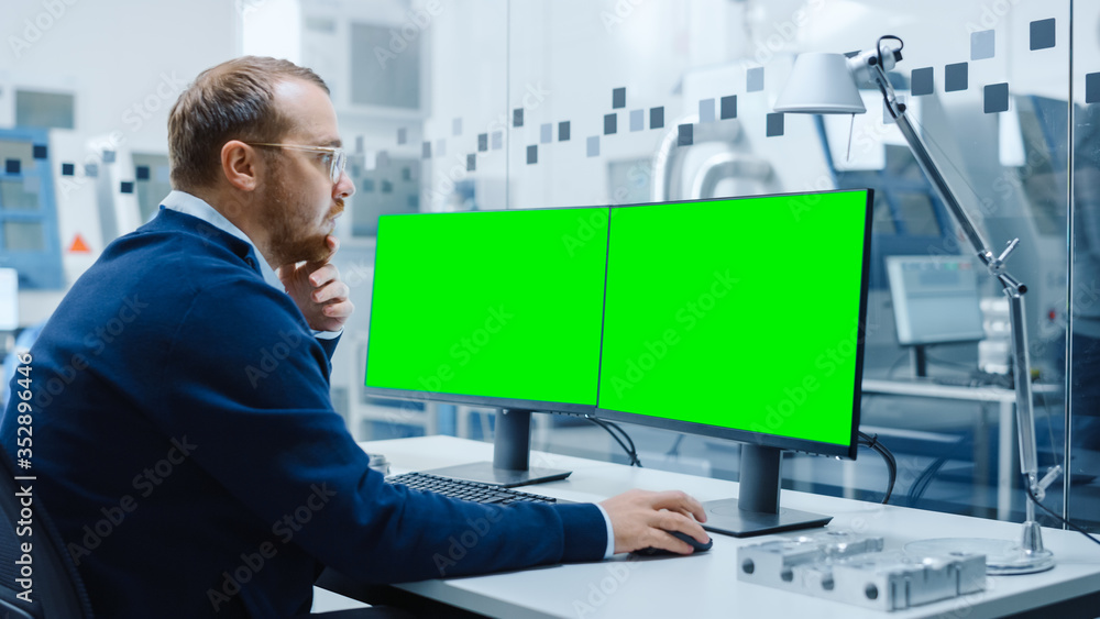 在个人电脑上工作的工业工程师，两个监视器屏幕是实物模型，绿屏，C