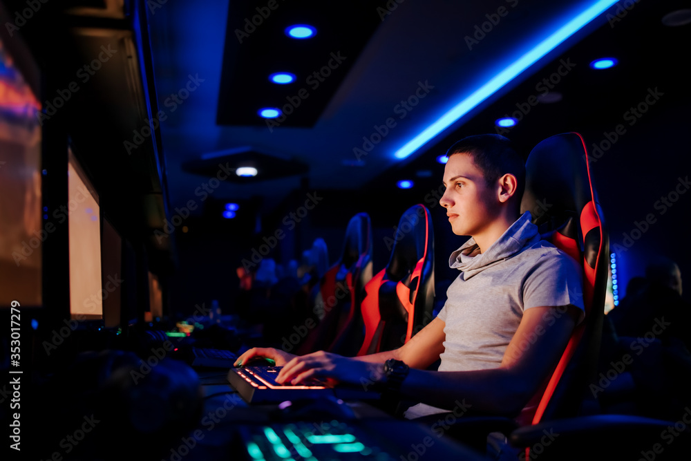 一位青少年玩家在现代游戏室玩电子游戏的侧视肖像。