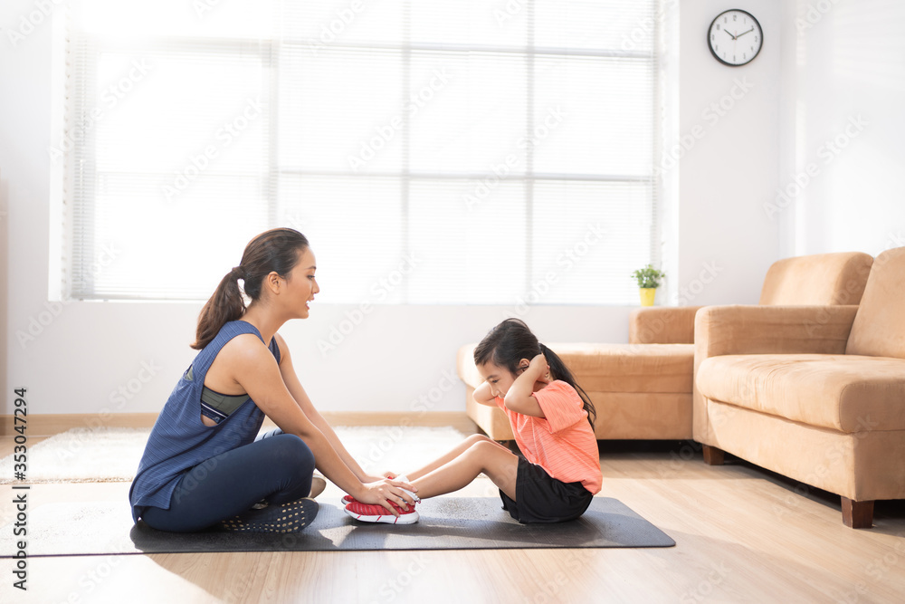 母亲和女儿在家锻炼他们在做仰卧起坐。