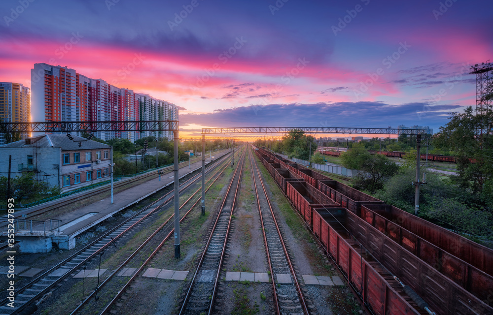 夏日色彩缤纷的日落下，火车站和货运列车的鸟瞰图。铁路俯视图