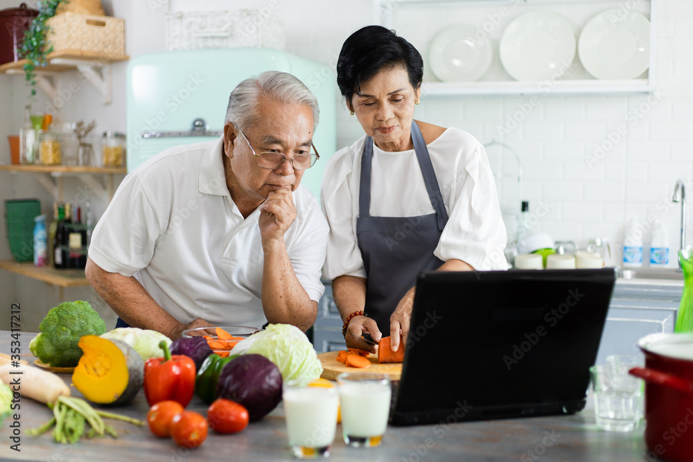 一对亚洲老年夫妇的肖像。在线烹饪教程在家里的厨房里。高级coupl