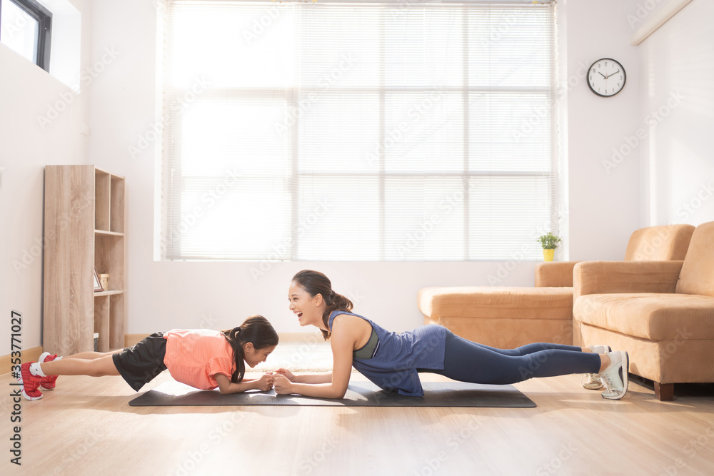 母亲和女儿在家锻炼他们在做平板运动