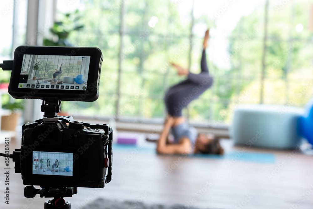 摄像机记录年轻的瑜伽大师用监视器进行肩部站立