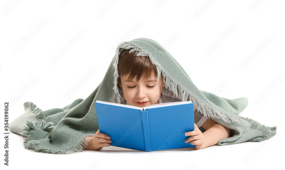 Little boy wrapped in plaid reading book on white background