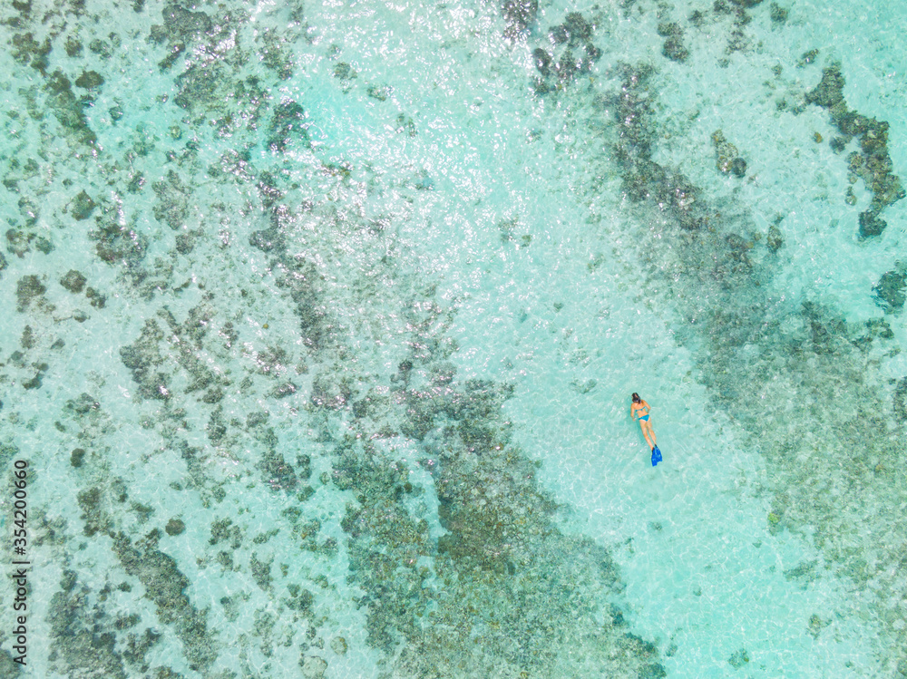 TOP DOWN: Female snorkeler dives around turquoise ocean and explores coral reef