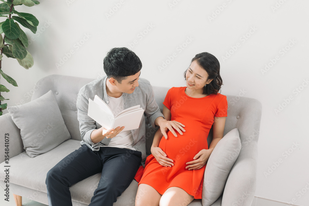 丈夫在家的沙发上为怀孕的妻子读书