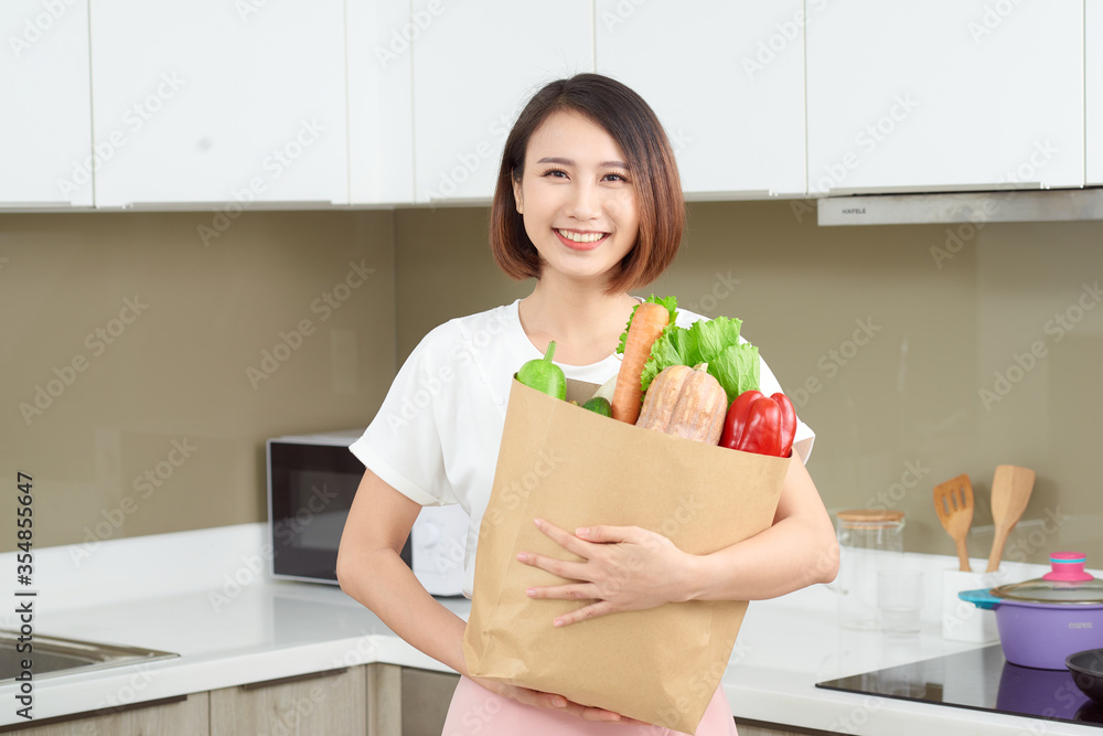 快乐的年轻亚洲女人，购物袋里有蔬菜。饮食理念。