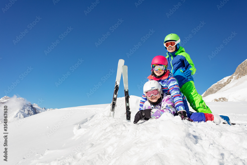 一堆又一堆的孩子躺在雪地里，背靠着滑雪板。