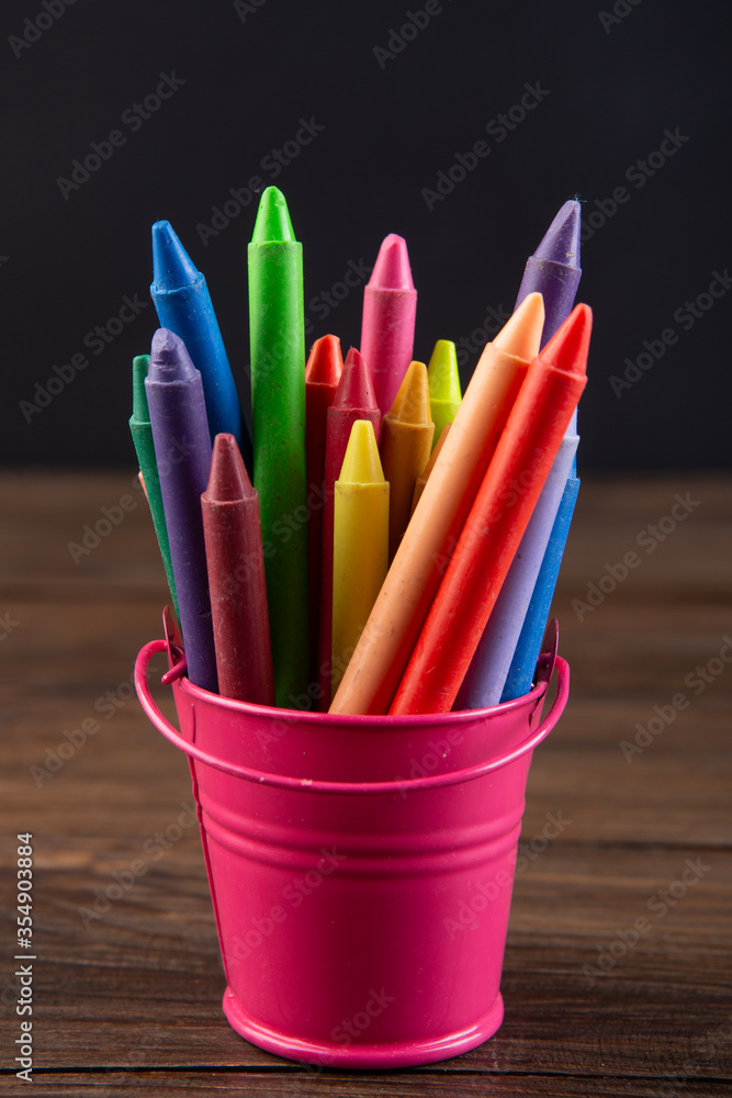木桌上的彩色蜡笔，黑板背景