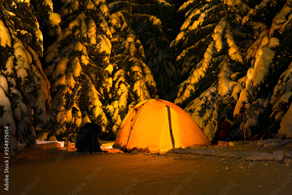 Tourist yellow tent in the winter forest