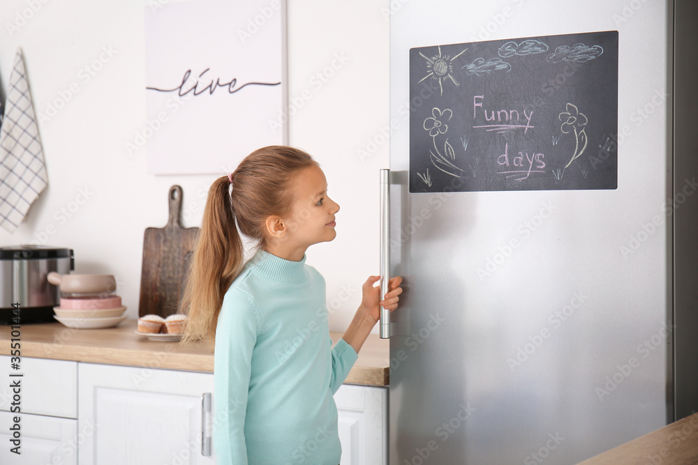 厨房冰箱黑板附近的小女孩