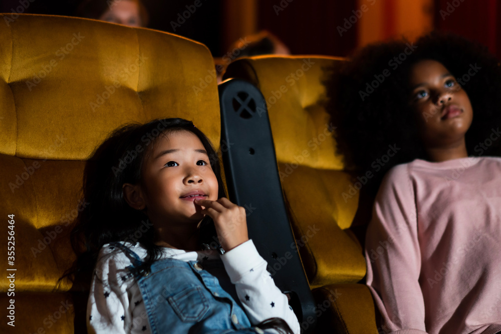 两个非洲和亚洲的孩子在电影院玩得很开心，喜欢看电影