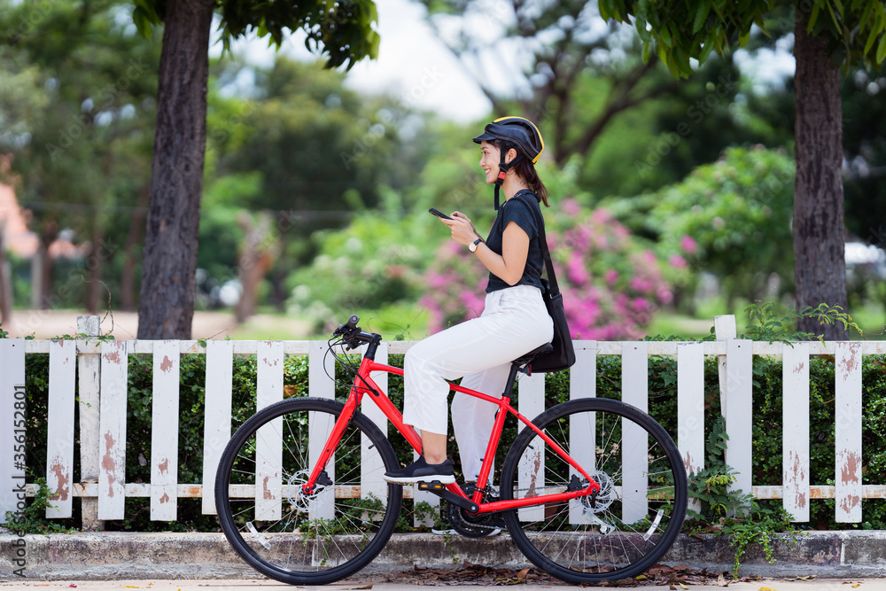 亚洲大学生骑自行车。她在打电话