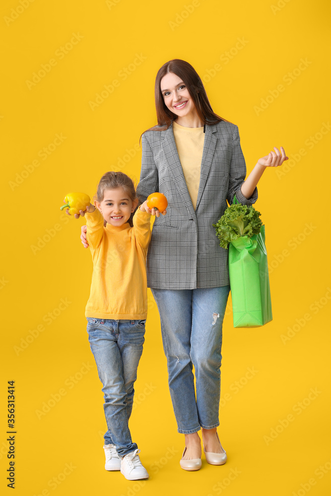 母亲和女儿用彩色背景的袋子装着食物