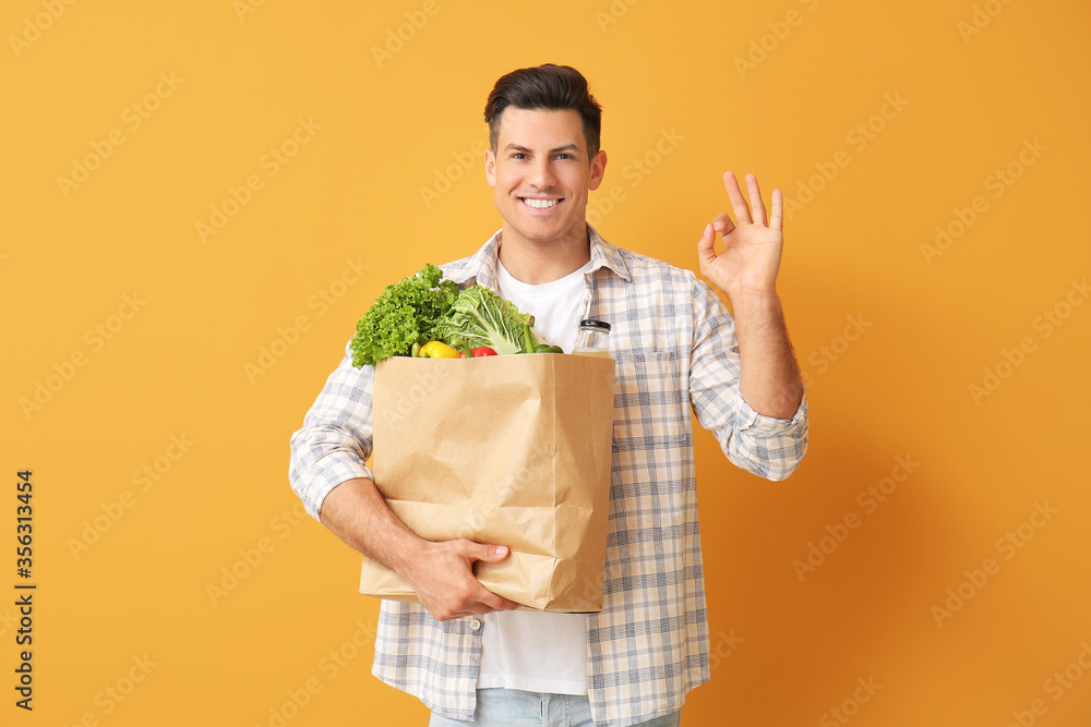 包里有食物的年轻人在彩色背景上显示OK手势