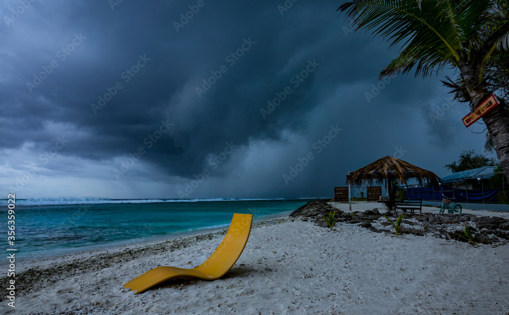 黑暗的暴风雨云层聚集在一个热带岛屿上，那里有田园诗般的白沙海岸