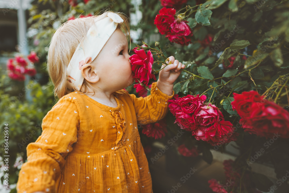闻花香的小女孩花园里的红玫瑰童年婴儿夏季生活方式芳香疗法和谐