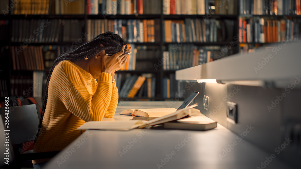 大学图书馆：疲惫的黑人女孩使用笔记本电脑，写论文，为课堂作业学习